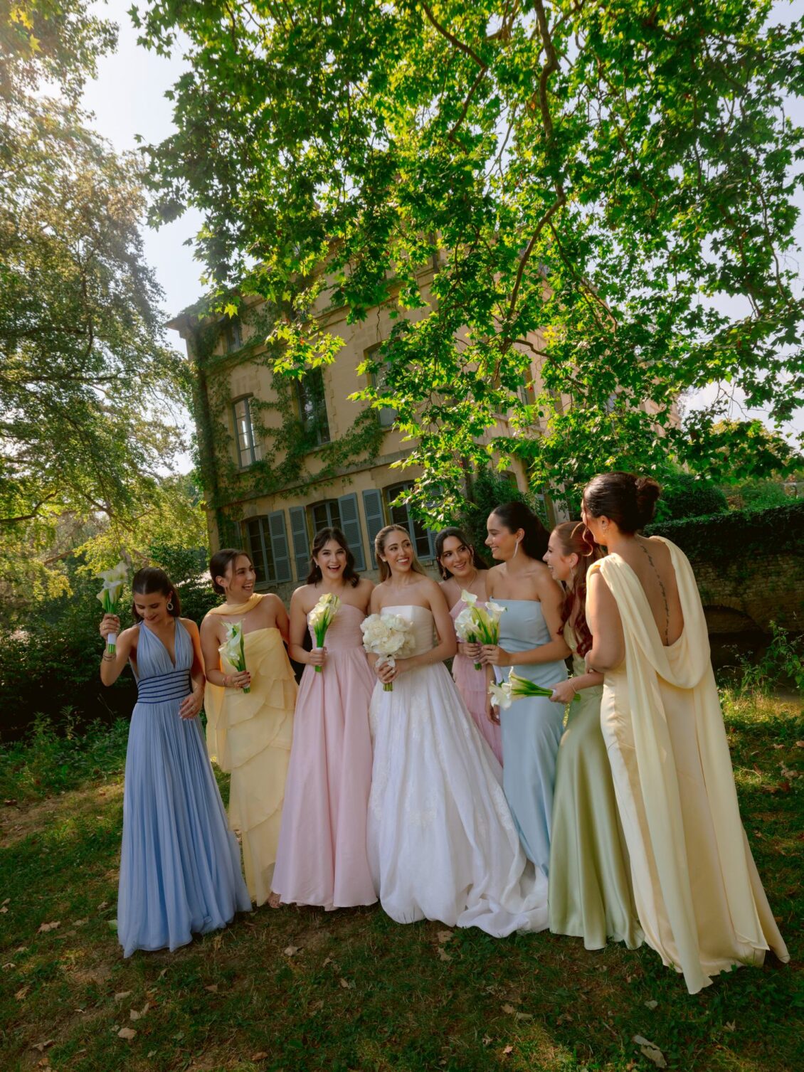 Lamya with her bridesmaids in blue, yellow, pink, mint and lilac gowns in the garden