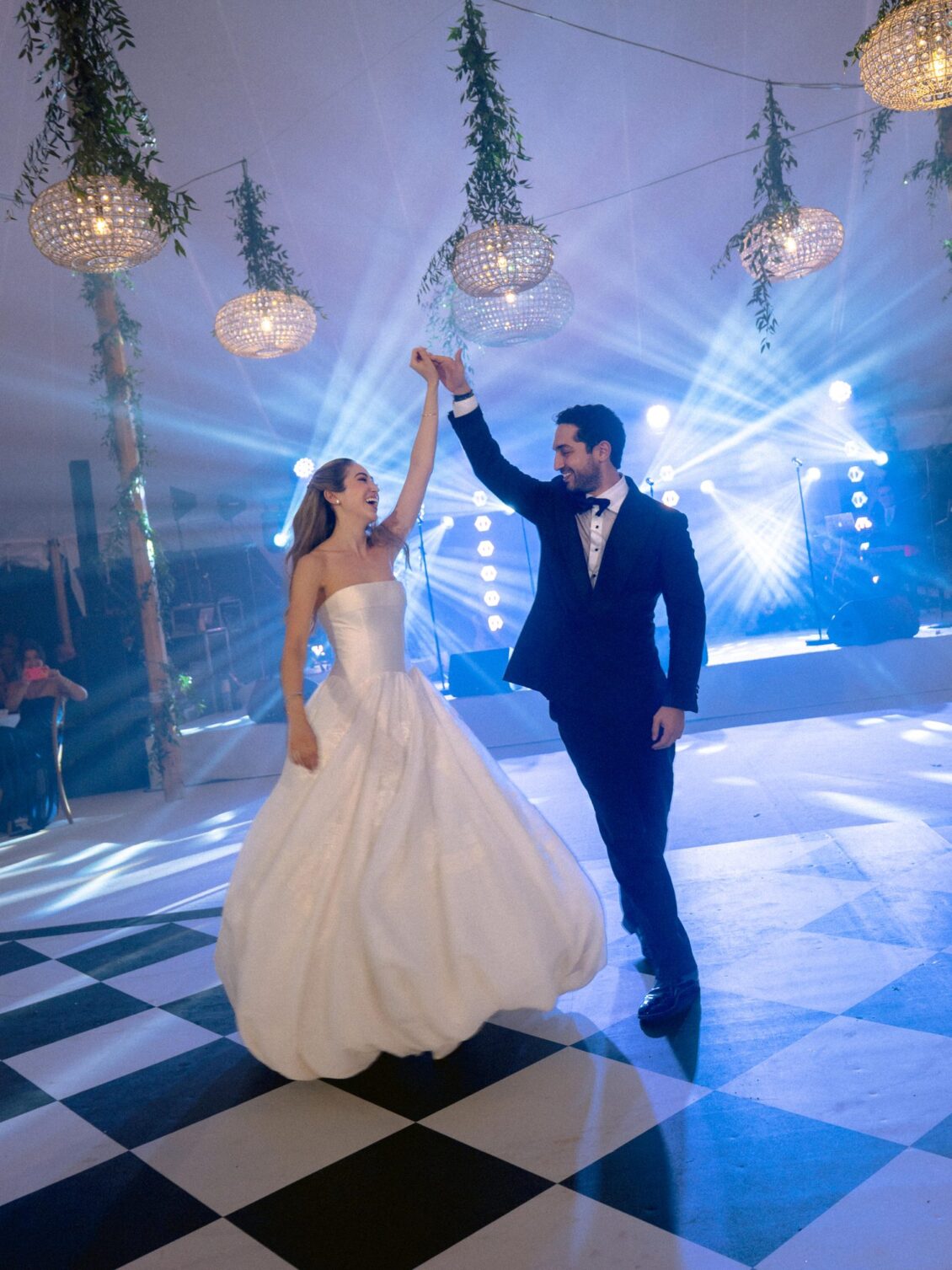 Sam twirls Lamya on the chequered dance floor under blue light during their first dance