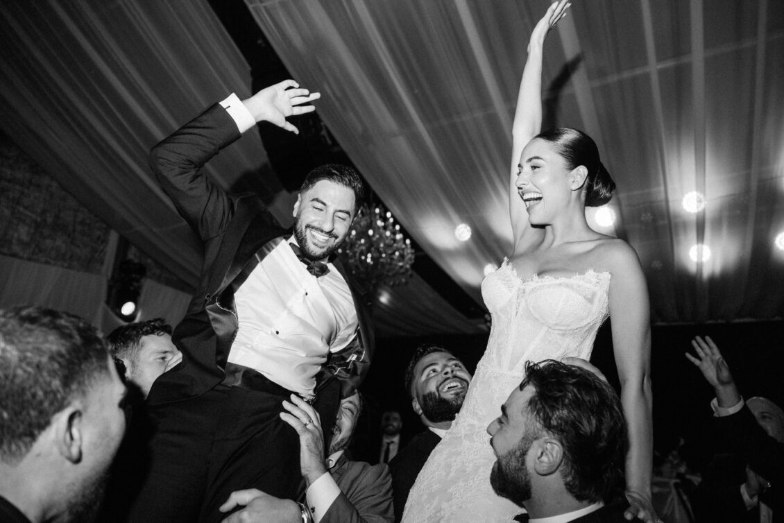Black and white photo of Lara and Alex lifted onto guests' shoulders on the dance floor