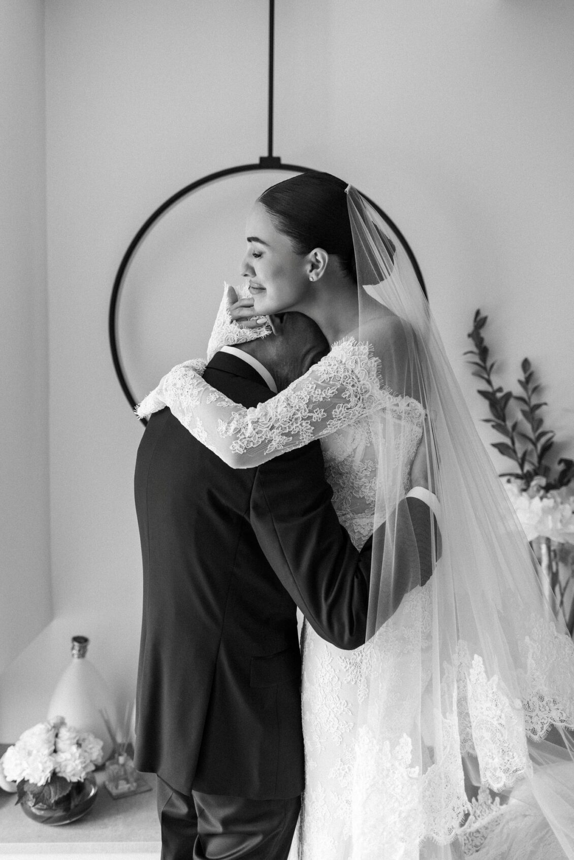 Black and white photo of Lara in her veil embracing her father in a tuxedo