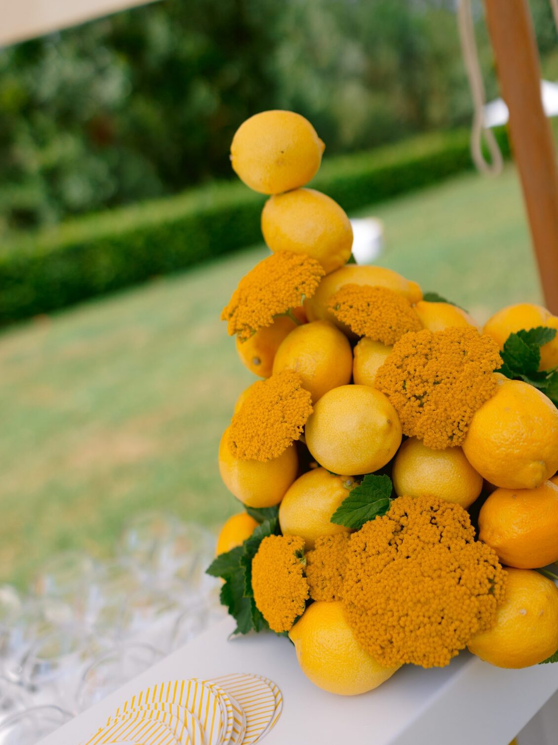 A stacked arrangement of lemons and orange marigolds on a white table