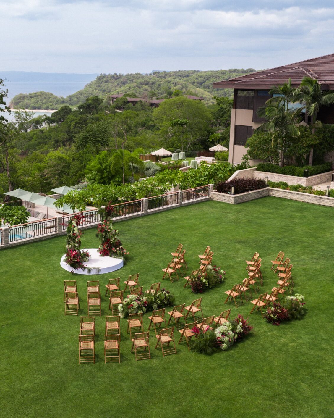 Red and pink floral ceremony design overlooking the coast at Nekajui, a Ritz-Carlton Reserve
