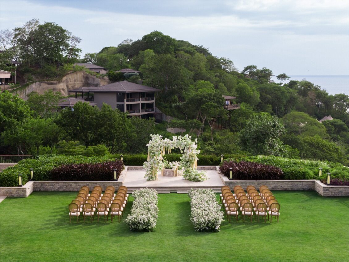 White floral wedding aisle and ceremony arch on a garden lawn at Nekajui, Costa Rica