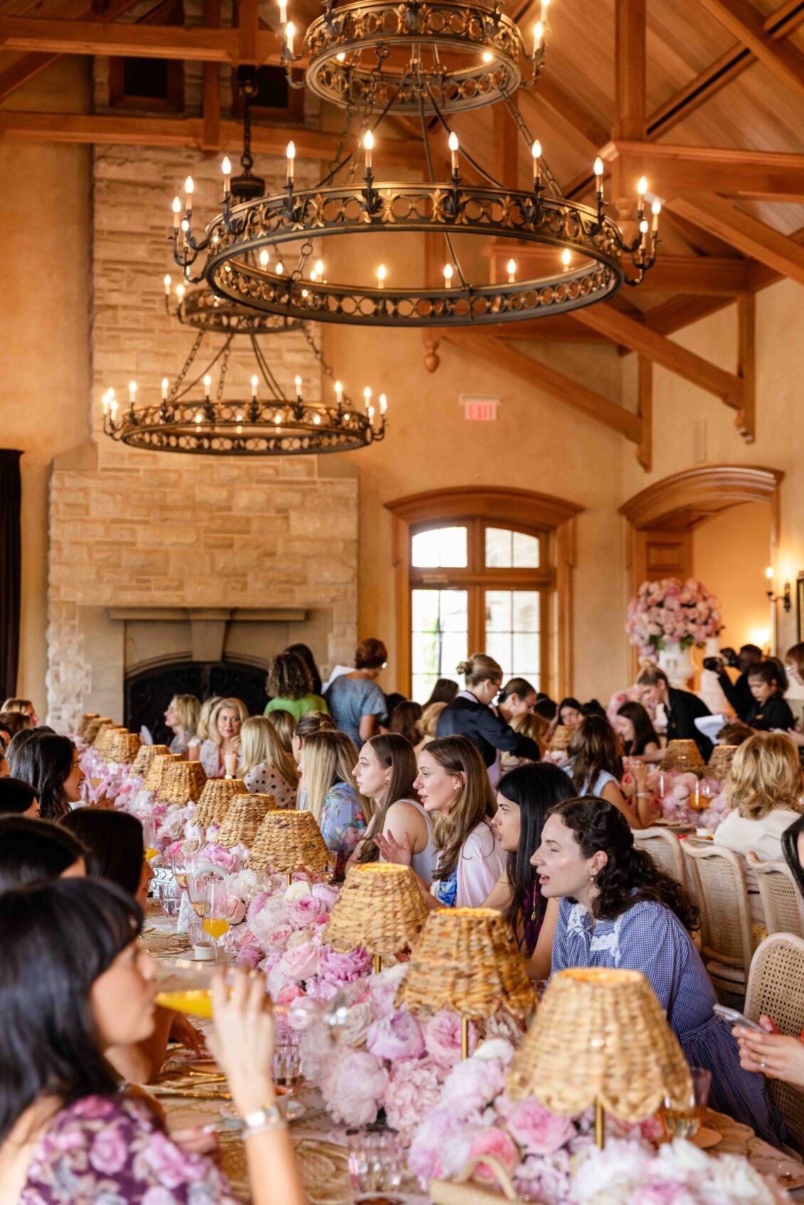 Guests dining beneath chandeliers and pink flowers
