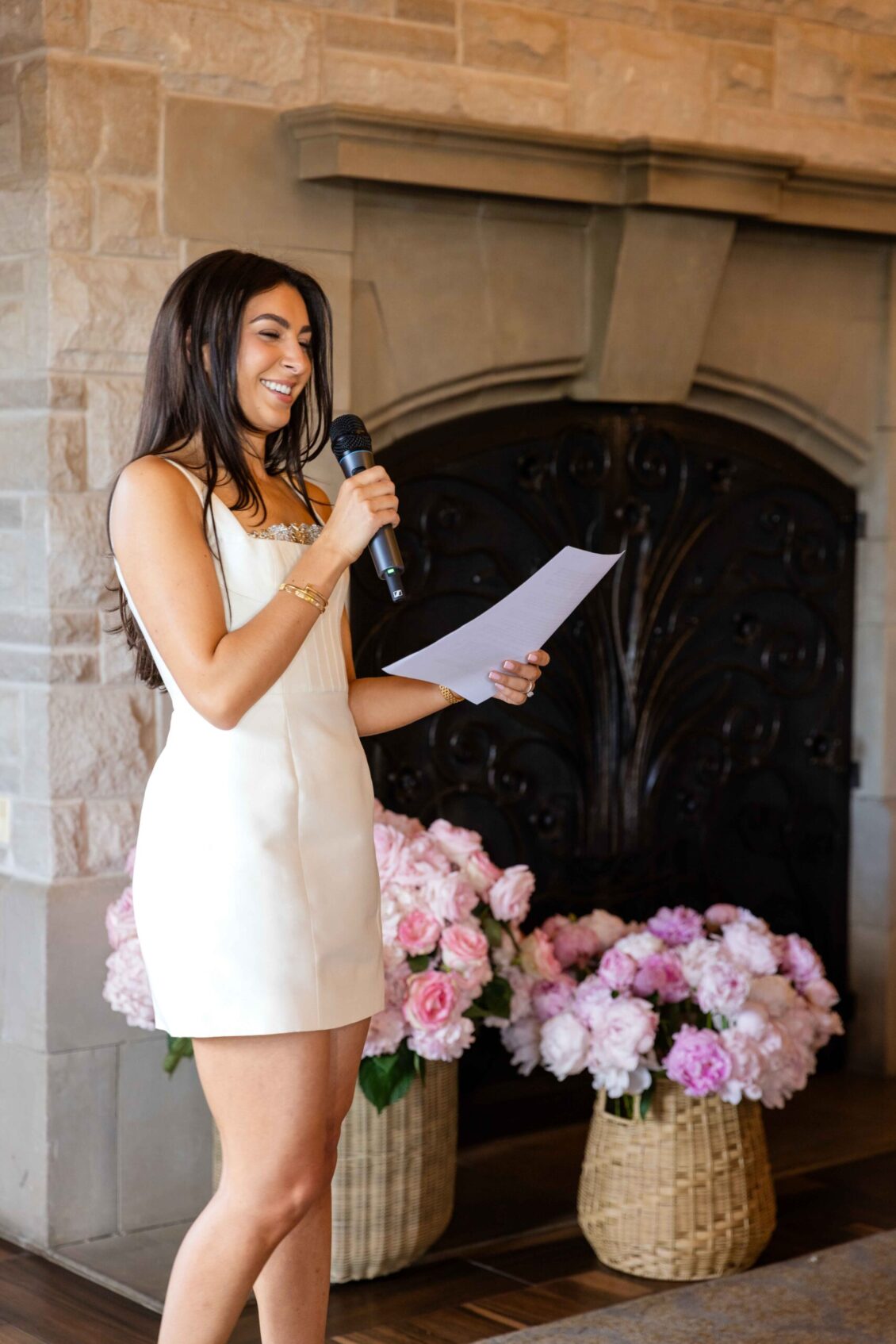 A guest in white reading a speech by the fireplace