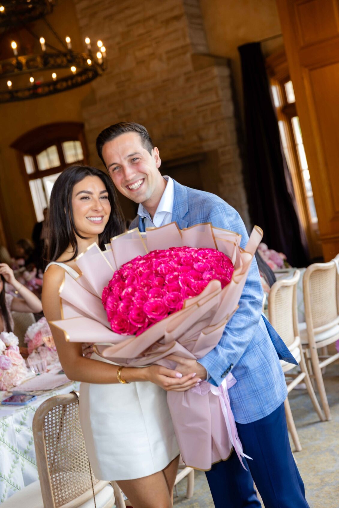 A couple embracing beside a vivid pink bouquet
