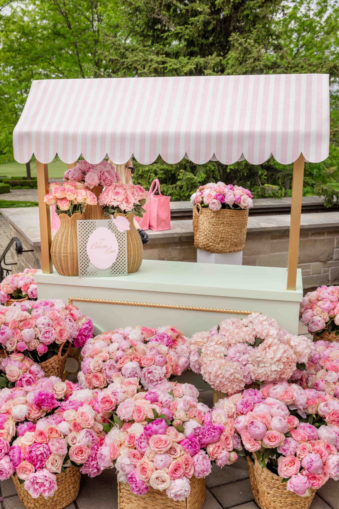 Guest gift stand styled with baskets and abundant pink flowers
