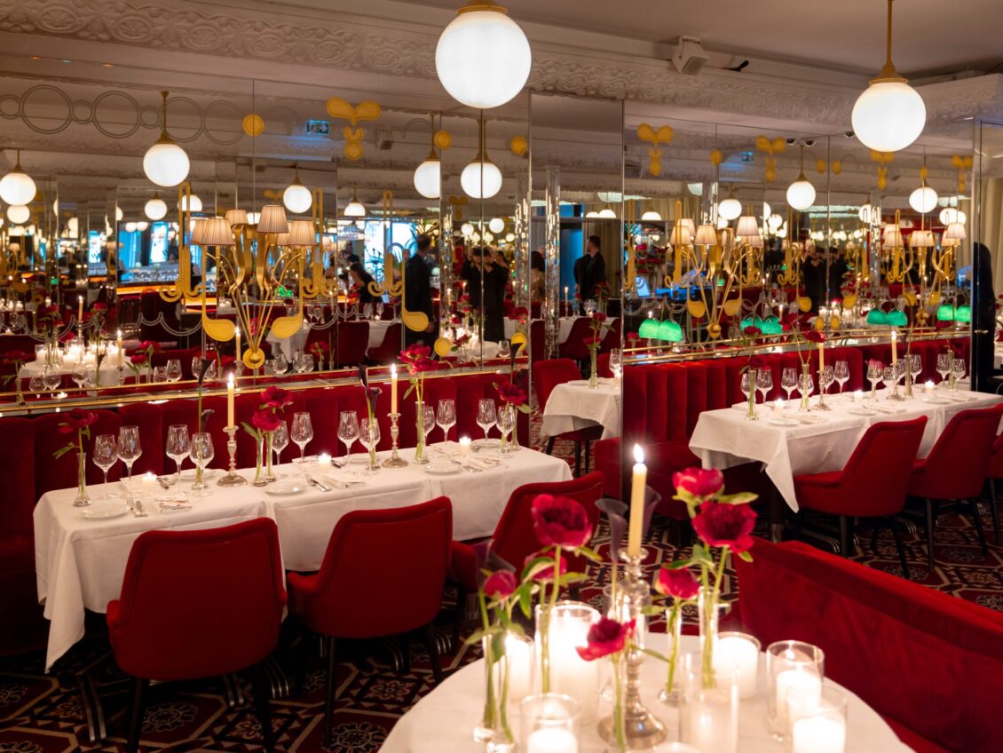The Thoumieux dining room in Paris set with white linen, red velvet chairs, globe lights, red peonies and candles