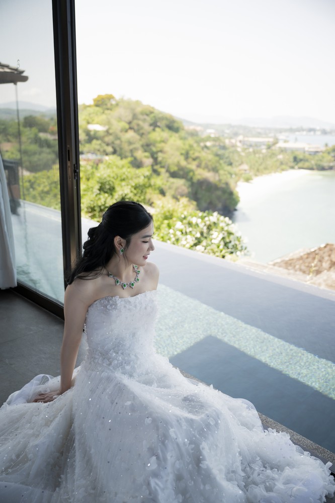 Vivian and Josen’s romantic destination wedding at Trisara Phuket — bride seated by a window in her lace gown overlooking the coast