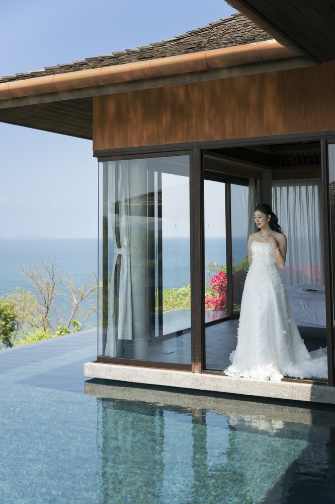 Vivian and Josen’s romantic destination wedding at Trisara Phuket — full-length bride portrait in a glass doorway beside the pool and sea