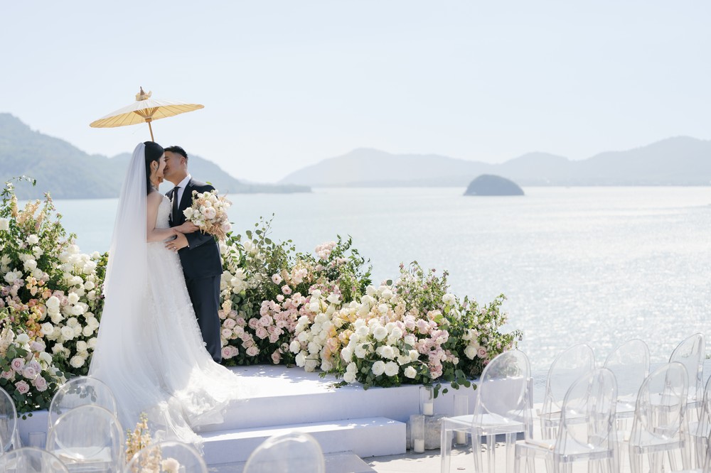 Vivian and Josen’s romantic destination wedding at Trisara Phuket — closer embrace at the flower-lined seaside altar