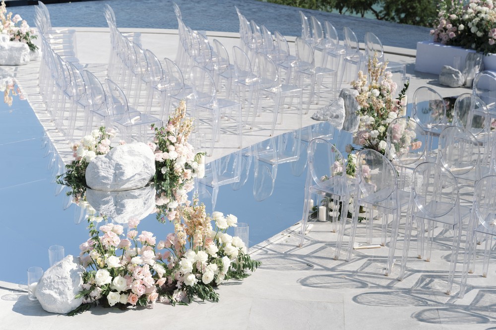 Vivian and Josen’s romantic destination wedding at Trisara Phuket — angled detail of the mirrored aisle, flowers, and transparent seating