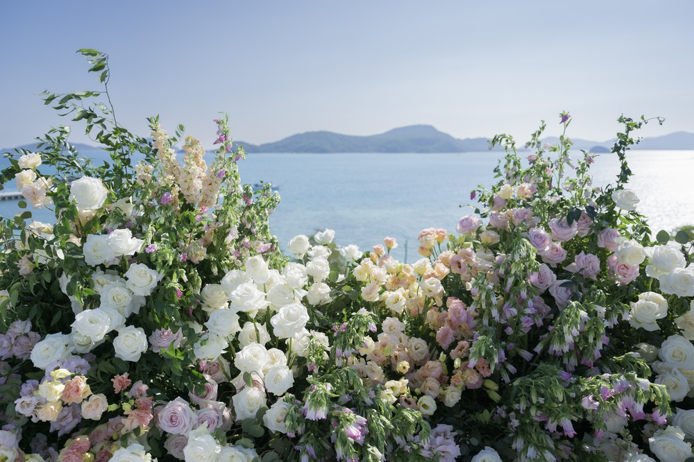Vivian and Josen’s romantic destination wedding at Trisara Phuket — pastel altar flowers against the sea and islands