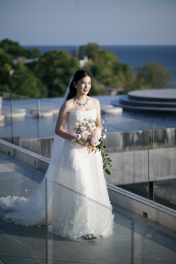 Vivian and Josen’s romantic destination wedding at Trisara Phuket — full-length bridal portrait beside the glass railing and sea