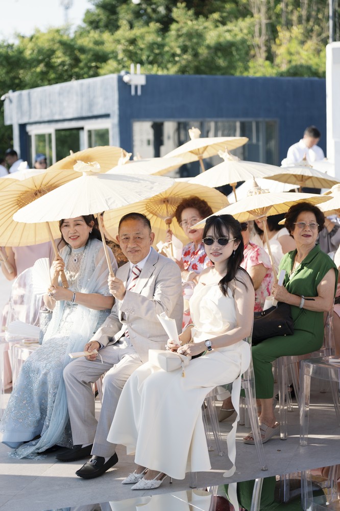 Vivian and Josen’s romantic destination wedding at Trisara Phuket — guests seated beneath parasols during the ceremony