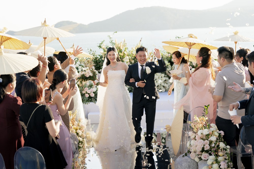 Vivian and Josen’s romantic destination wedding at Trisara Phuket — newlyweds walking back up the aisle as guests celebrate