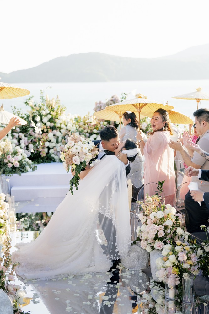 Vivian and Josen’s romantic destination wedding at Trisara Phuket — couple sharing a dipped kiss during the recessional
