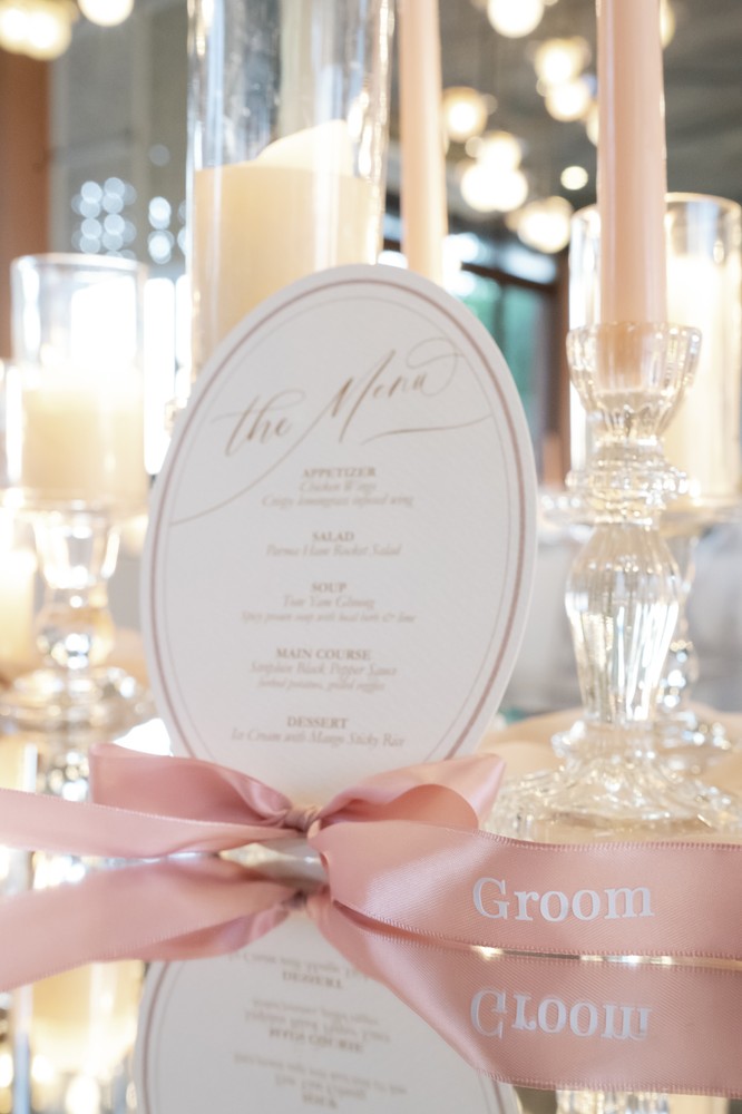 Vivian and Josen’s romantic destination wedding at Trisara Phuket — personalized oval menu and pink-ribbon detail