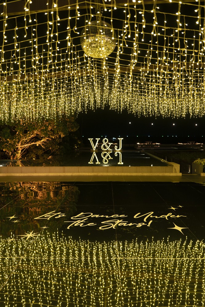 Vivian and Josen’s romantic destination wedding at Trisara Phuket — vertical nighttime pool scene with light reflections