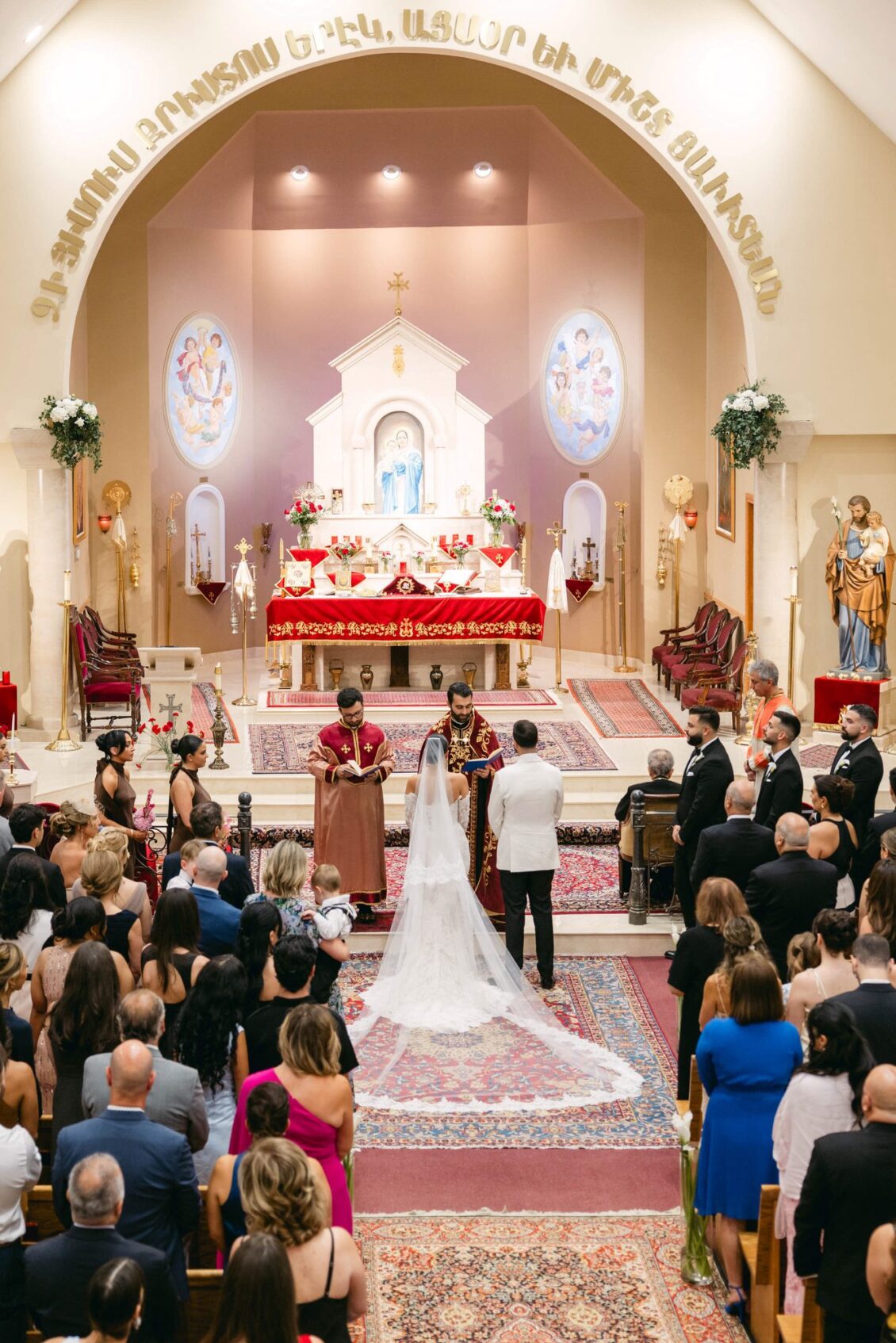 Wide view of the church during the ceremony with the couple at the altar and guests in the pews