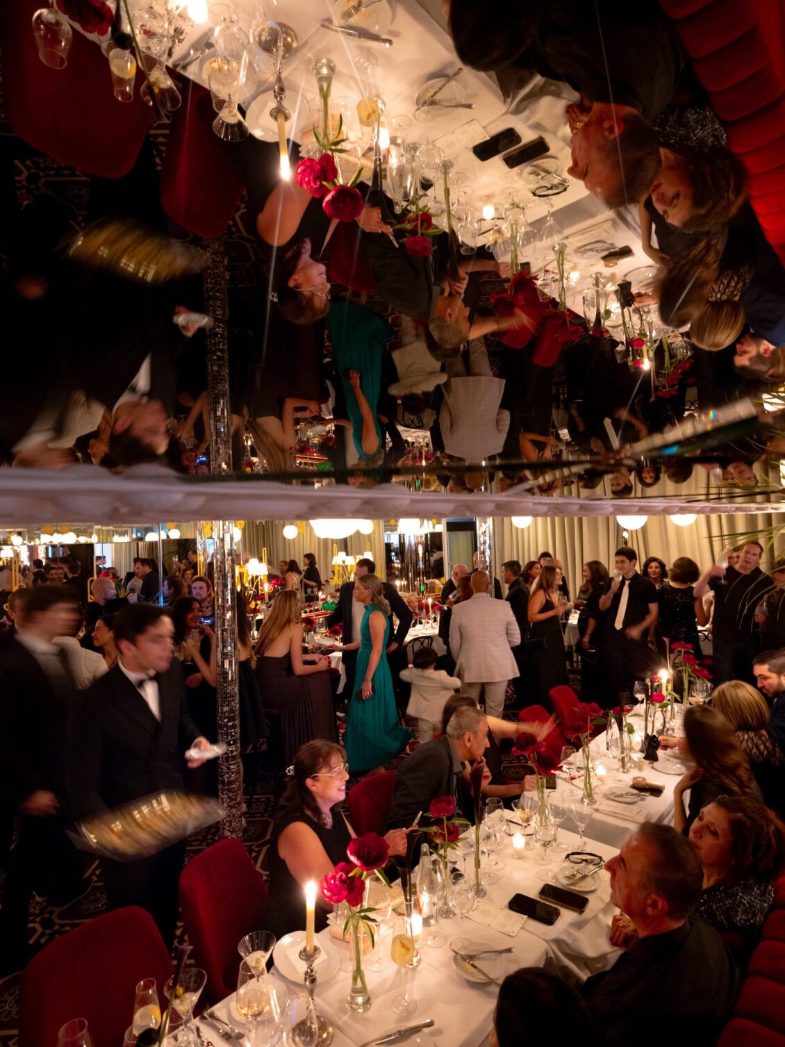 Guests seated at long tables reflected in the mirrored ceiling of Thoumieux during the welcome dinner