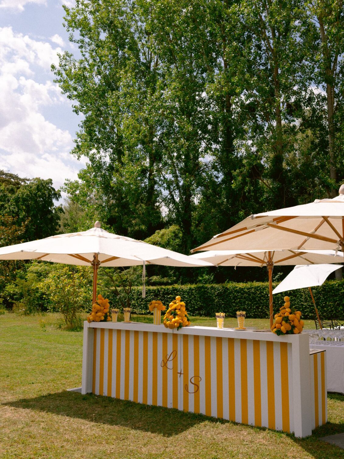 A yellow-and-white striped bar beneath white parasols on the lawn at Domaine de Primard
